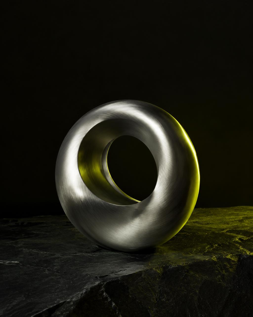 Brushed metal ring sculpture on dark stone